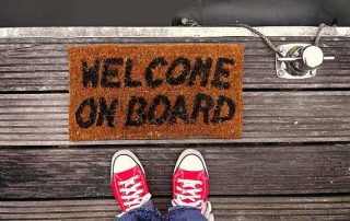 Turnschuhe rot vor Fußläufer mit Aufschrift WELCOME ON BOARD